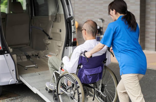 A OpenArms HCS caregiver helps an elderly man adjust his sweater in a bathroom, emphasizing dignity and personalized care during daily routines.