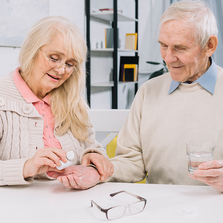 A I Love Open Arms caregiver and an elderly woman smile together as they tend to potted plants outdoors, emphasizing companionship and shared hobbies.